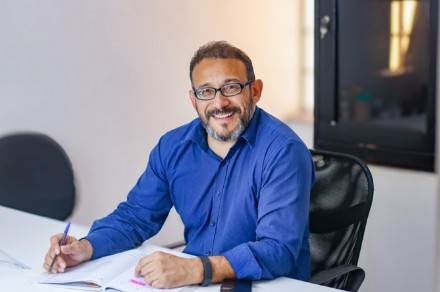 Antônio Azarias, da Excelência Contábil, sorrindo em sua mesa de trabalho