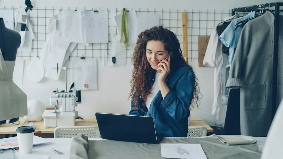 Empreendedora sorrindo ao telefone enquanto trabalha no laptop